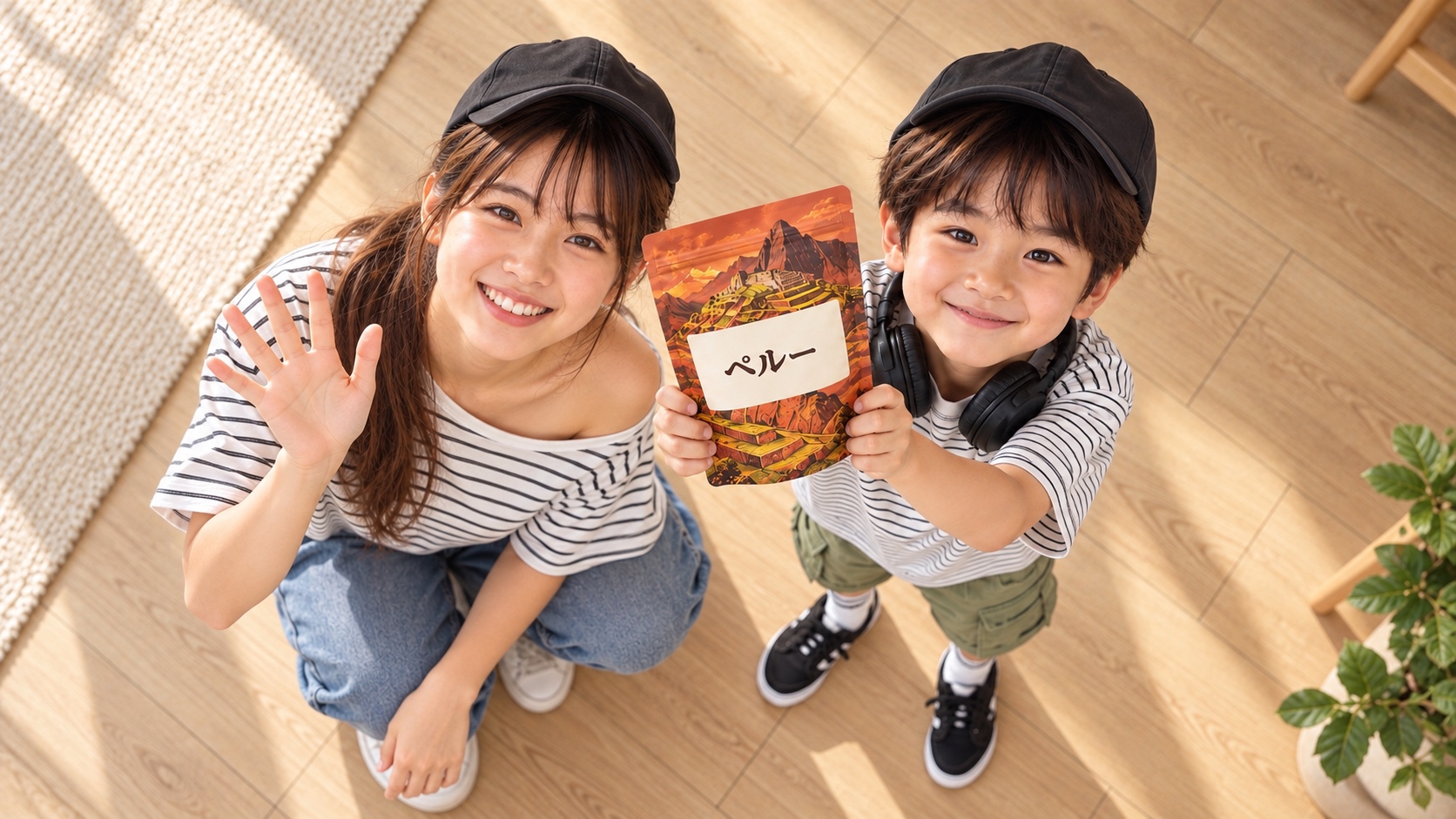 ペルーの袋を掲げるYUTAの隣で、帽子とボーダーの肩出し服を着たYUMEがしゃがんで笑顔で手を振る様子