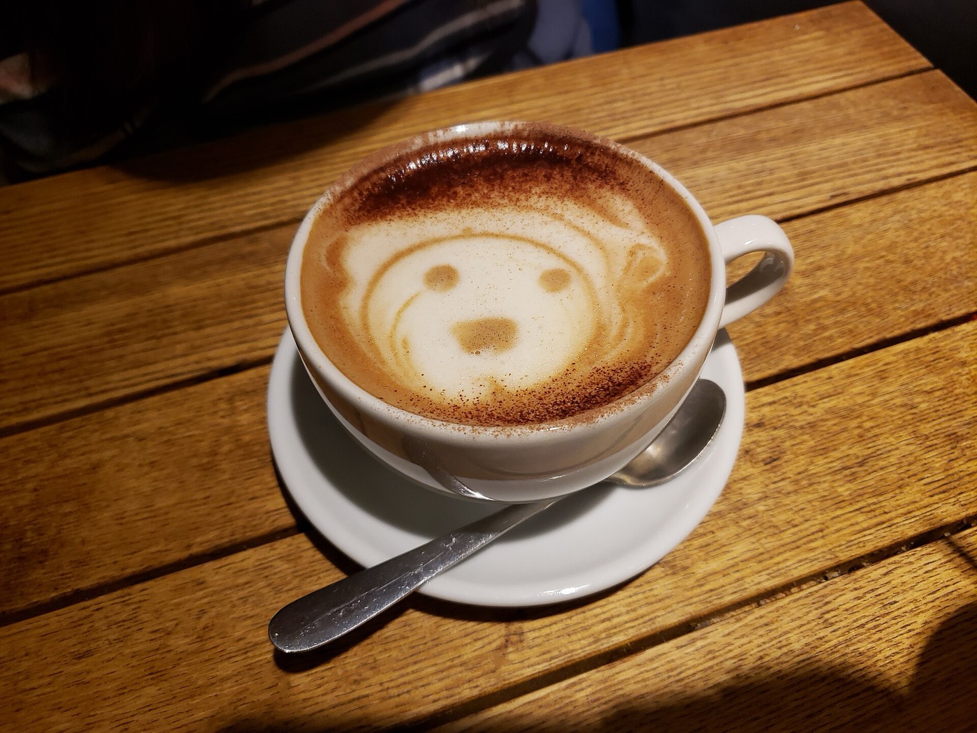 ココアパウダーをふりかけた泡の上にラテアートを描いたカフェモカ