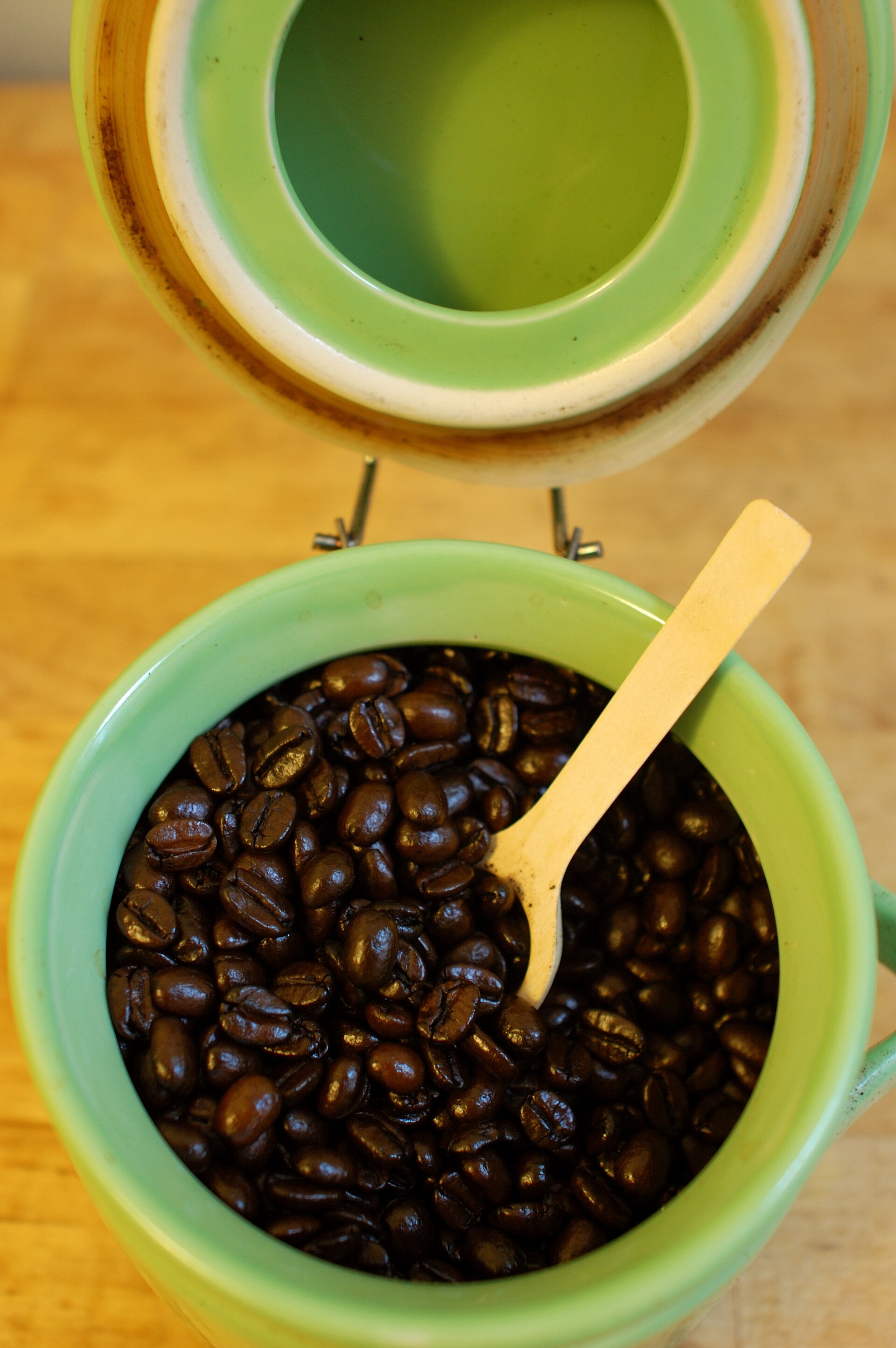 焙煎したコーヒー豆を入れた密閉キャニスターと木製スプーン