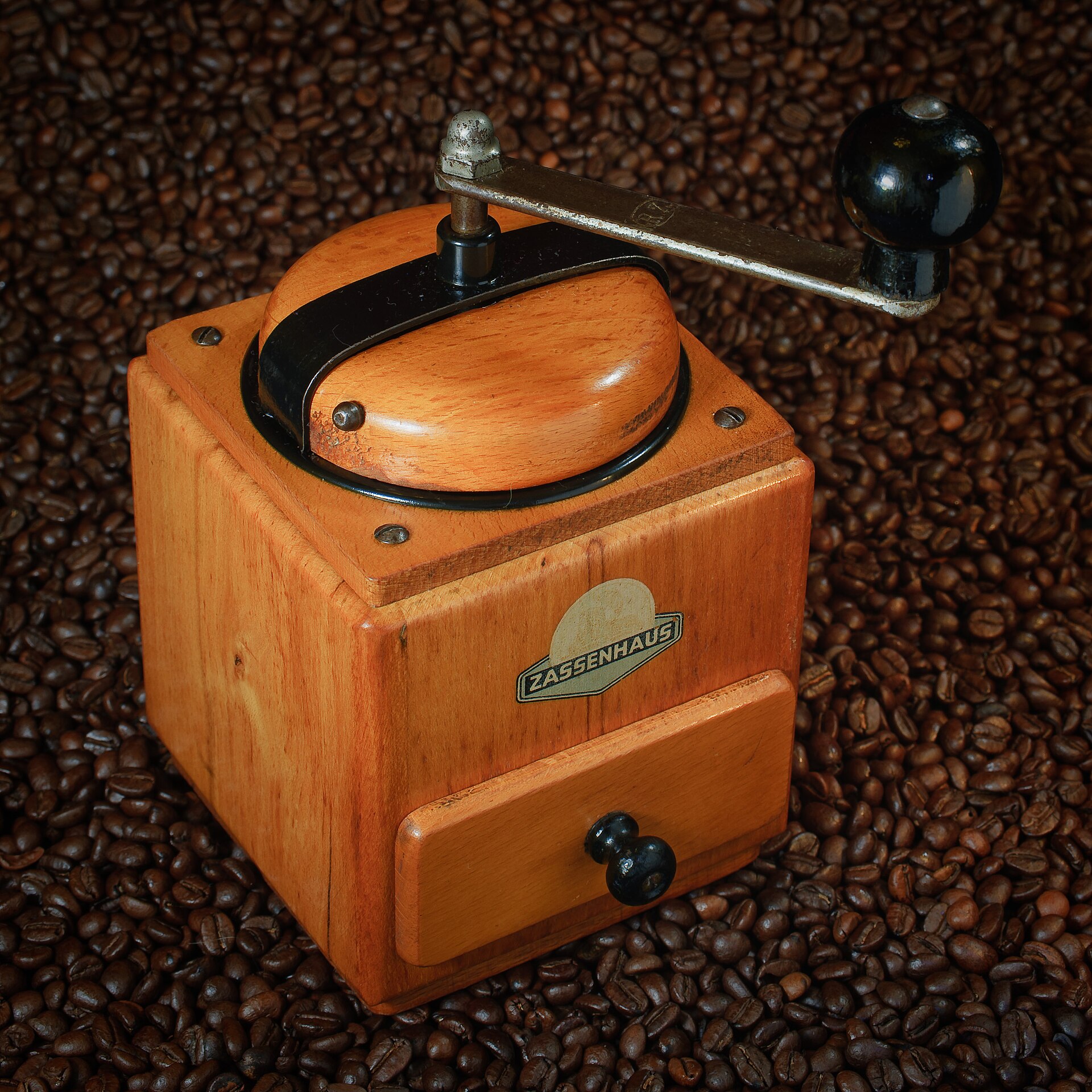 クランク付きの木製手挽きコーヒーミルとコーヒー豆