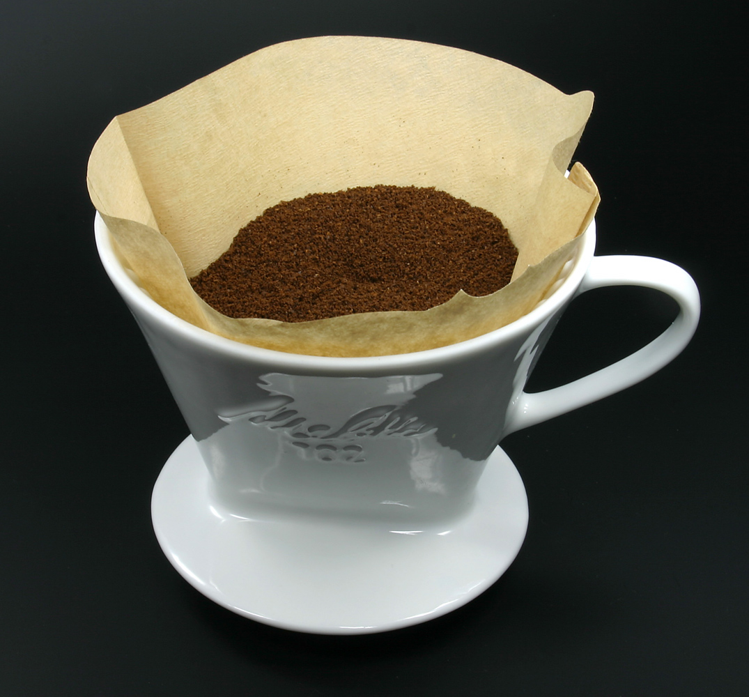 ドリッパーにセットした茶色のペーパーフィルターと挽いたコーヒー粉